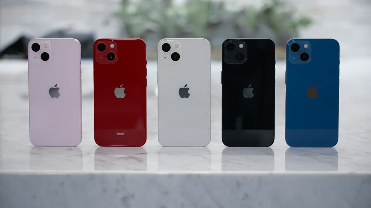 Five iPhone 13 phones in different colours lined up on a table
