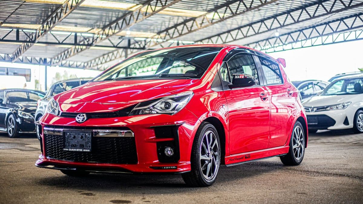 A red Toyota Vitz at a car yard