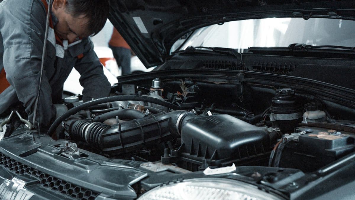 A mechanic checking a car's engine with the bonnet open